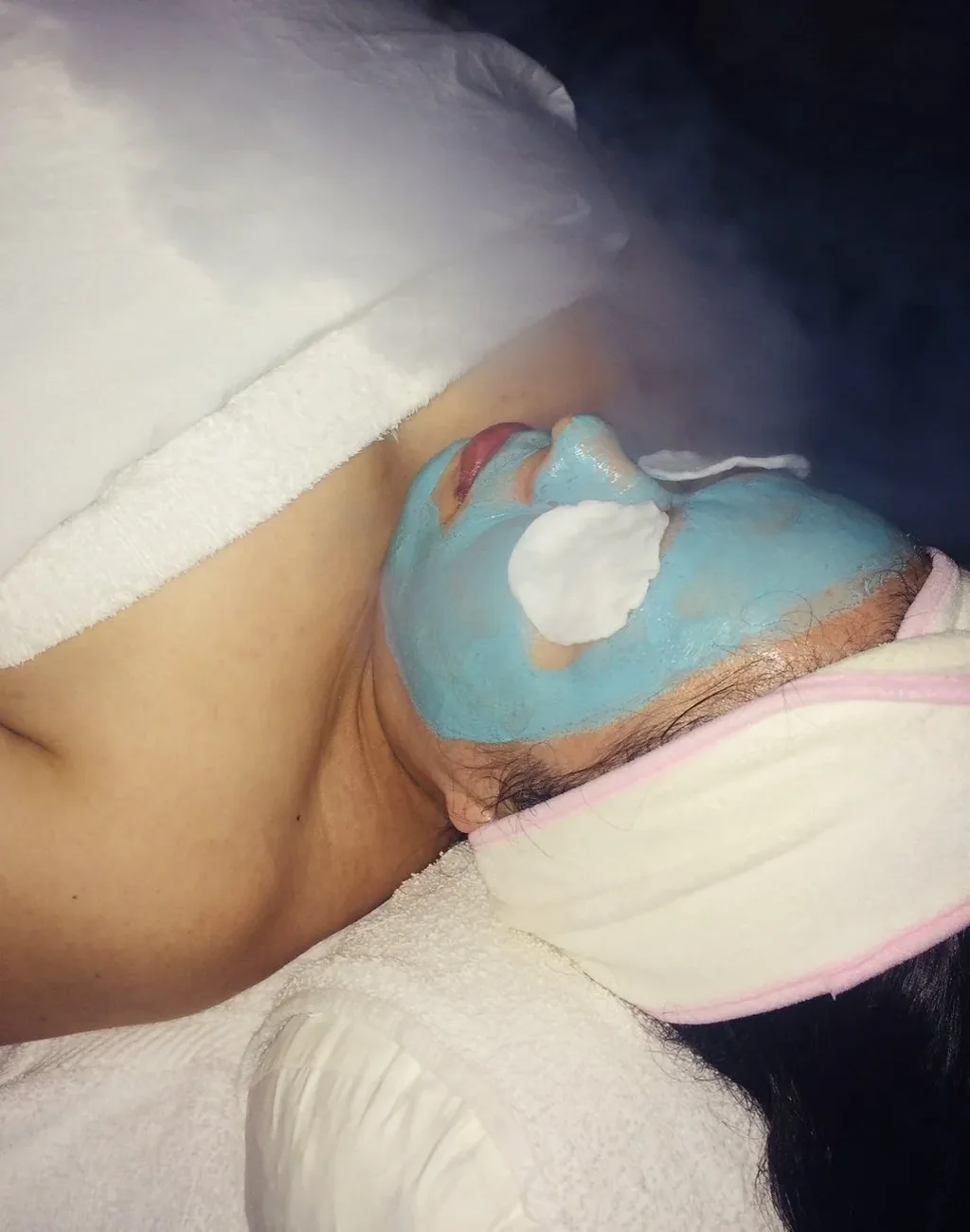 A client resting under steam with a treatment mask applied during a facial at Clean Skin